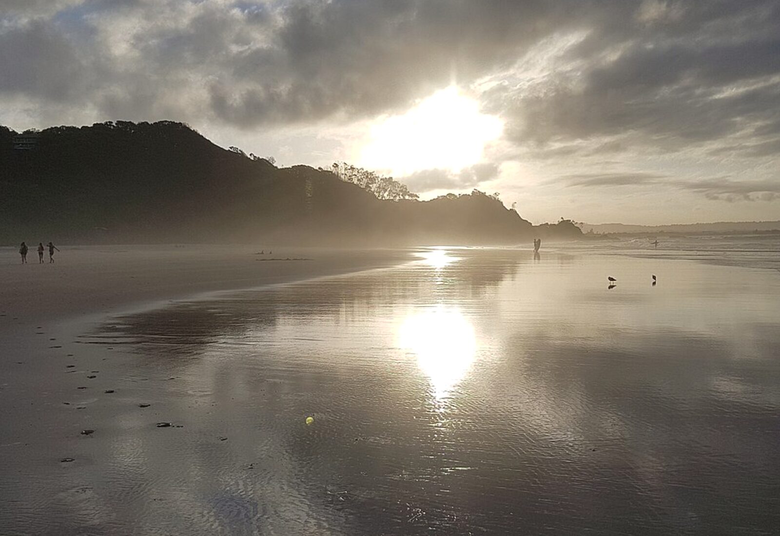 Wategos Beach at Byron Bay in low golden light with the Cape Byron headland behind