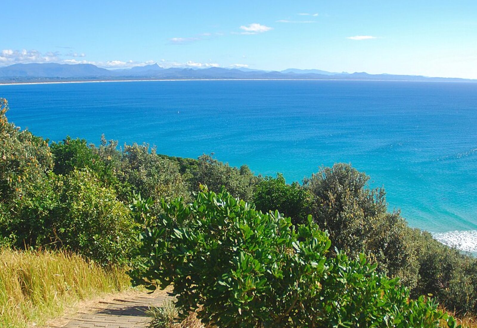The Cape Byron walking track climbing above turquoise water and coastal scrub
