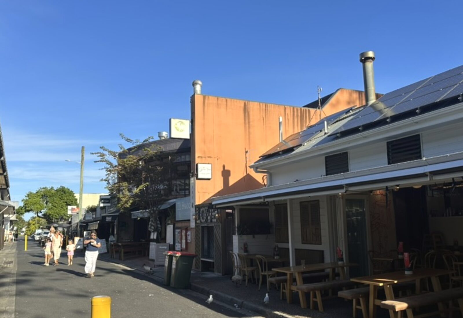 Footpath and shopfronts on a street in central Byron Bay on a clear morning